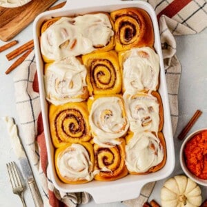 pumpkin cinnamon rolls in a dish with frosting