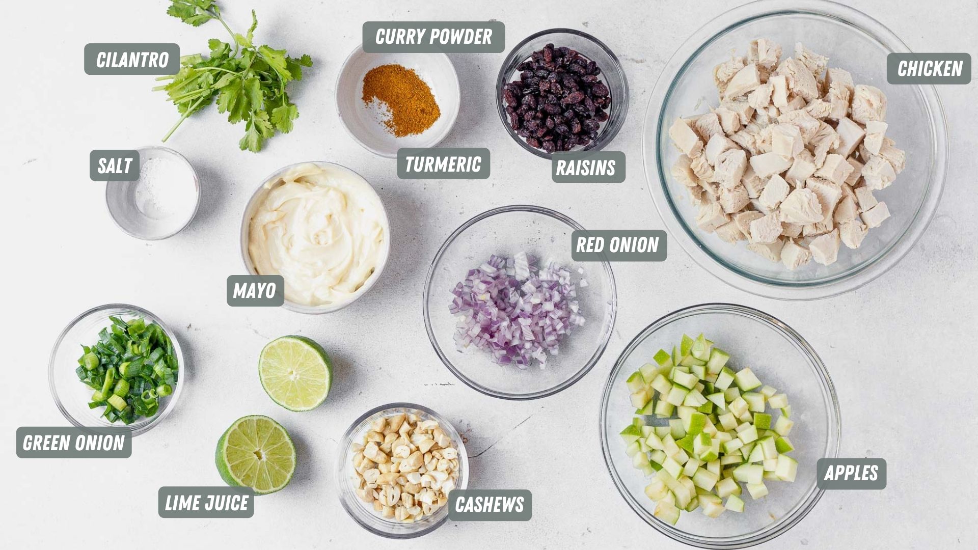 ingredients for curry chicken salad laid out on a counter in glass bowls