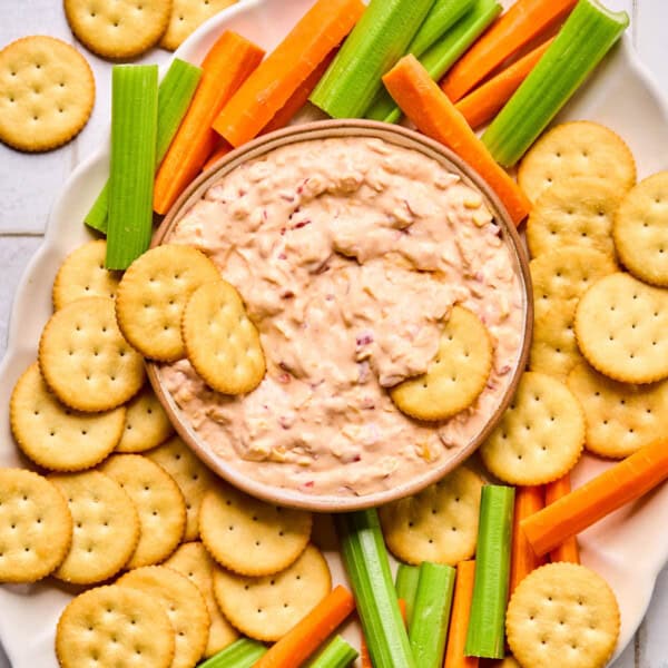 pimento cheese dip in a bowl surrounded by Ritz crackers and carrot and celery sticks