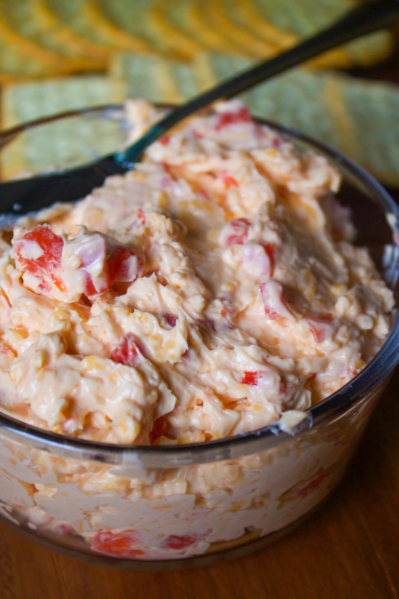 cheese spreader dipped into pimento cheese in a glass bowl