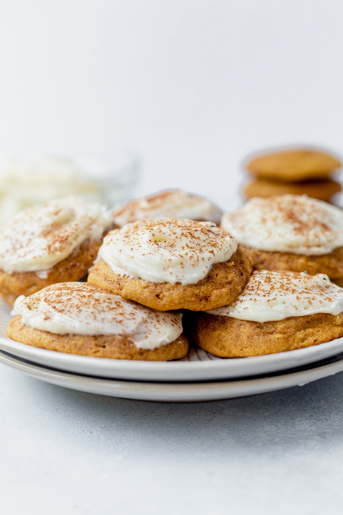 soft pumpkin cookies with cream cheese frosting on a white plate