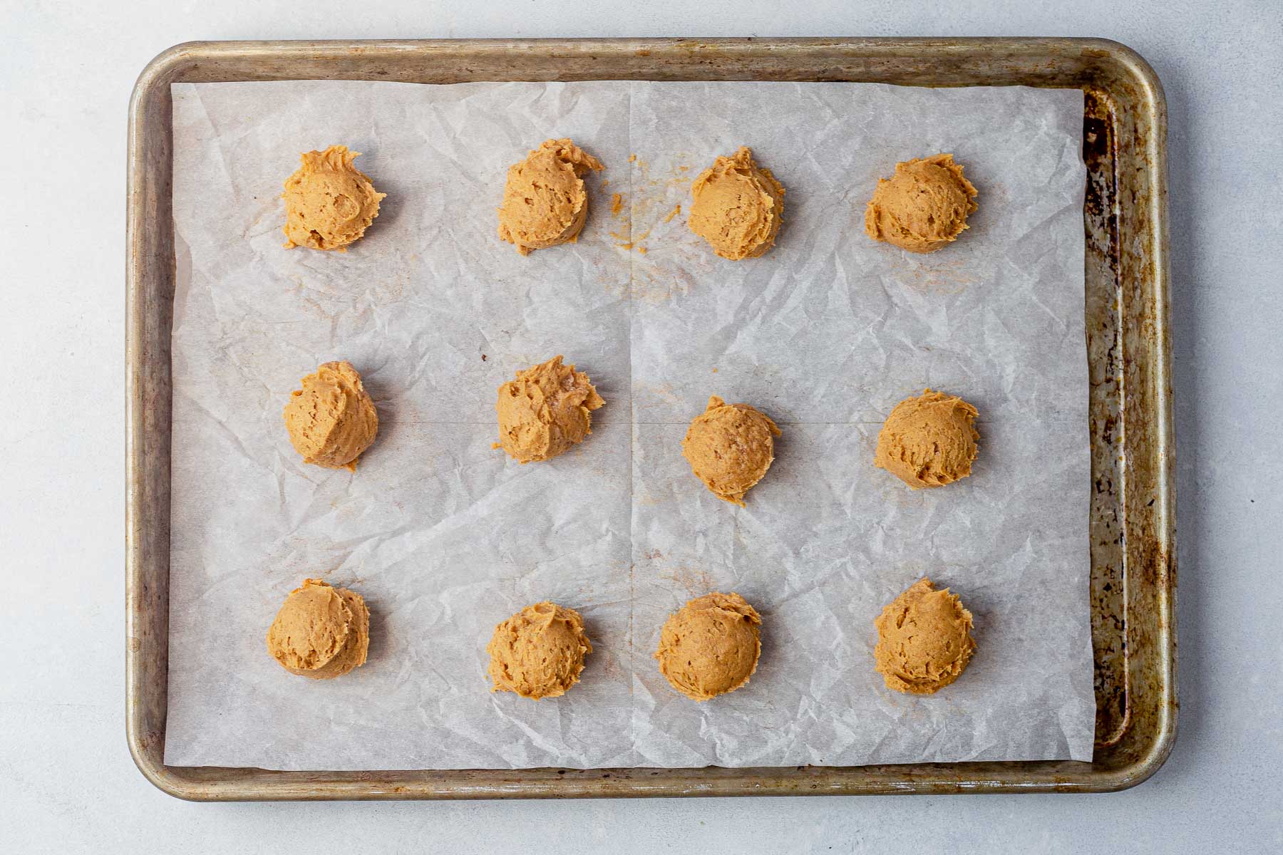 pumpkin cookies arranged on a baking sheet with parchment paper