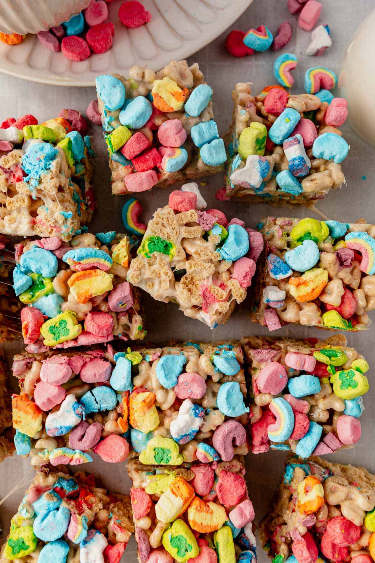 a batch of lucky charms rice krispie treats cut on a piece of parchment paper