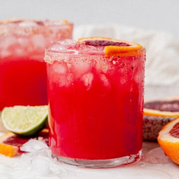 a blood orange margarita in a glass with crushed ice