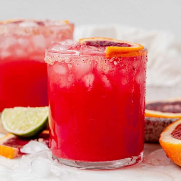 a blood orange margarita in a glass with crushed ice