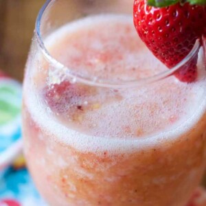 frozen sangria in a glass short wine glass with a strawberry garnishing the glass