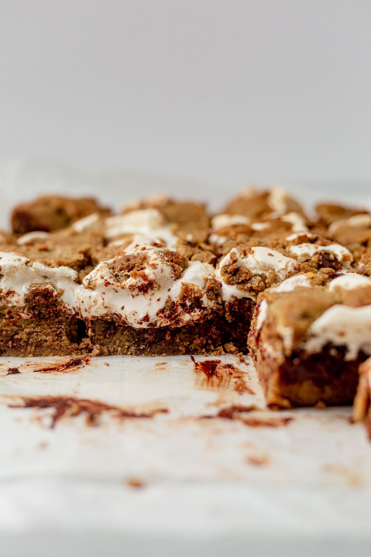 cookie smores bars on parchment paper with marshmallow creme oozing out