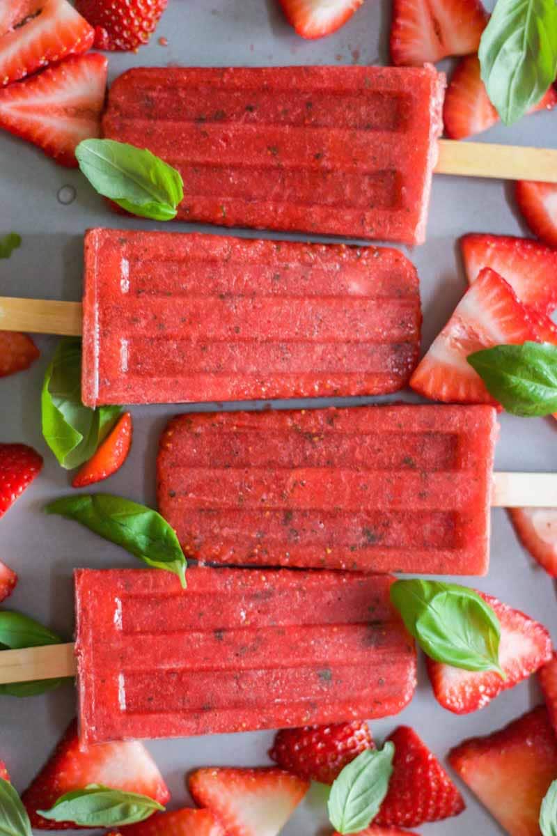 Paleo and healthy three ingredient strawberry basil popsicles! This recipe is easy to make and made with real strawberries, basil and honey. Blend them in your blender and pour in popsicles molds. Freeze for a couple of hours and you have a vegan, paleo and gluten free dessert recipe.