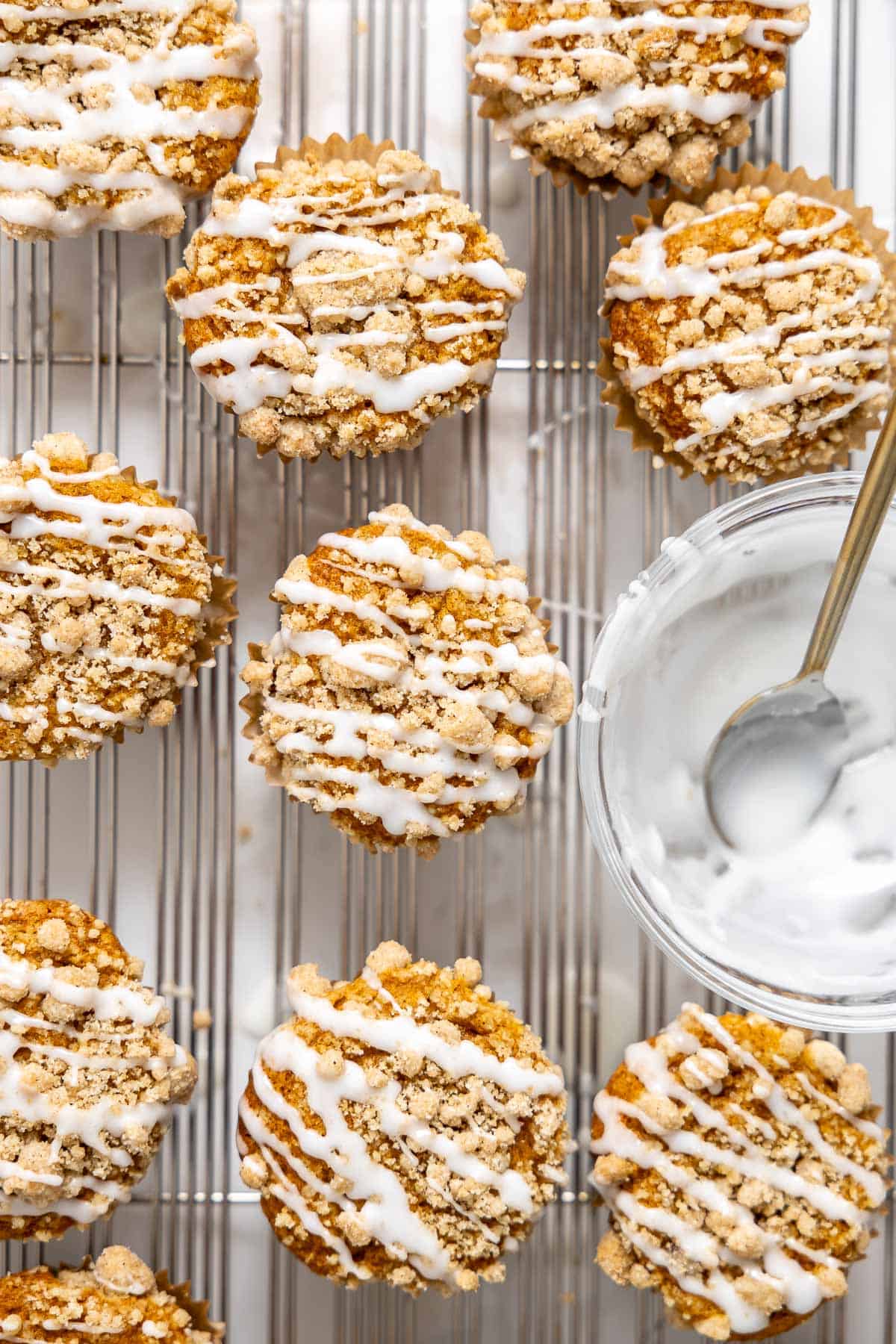 pumpkin streusel muffins with icing on a cooling rack.