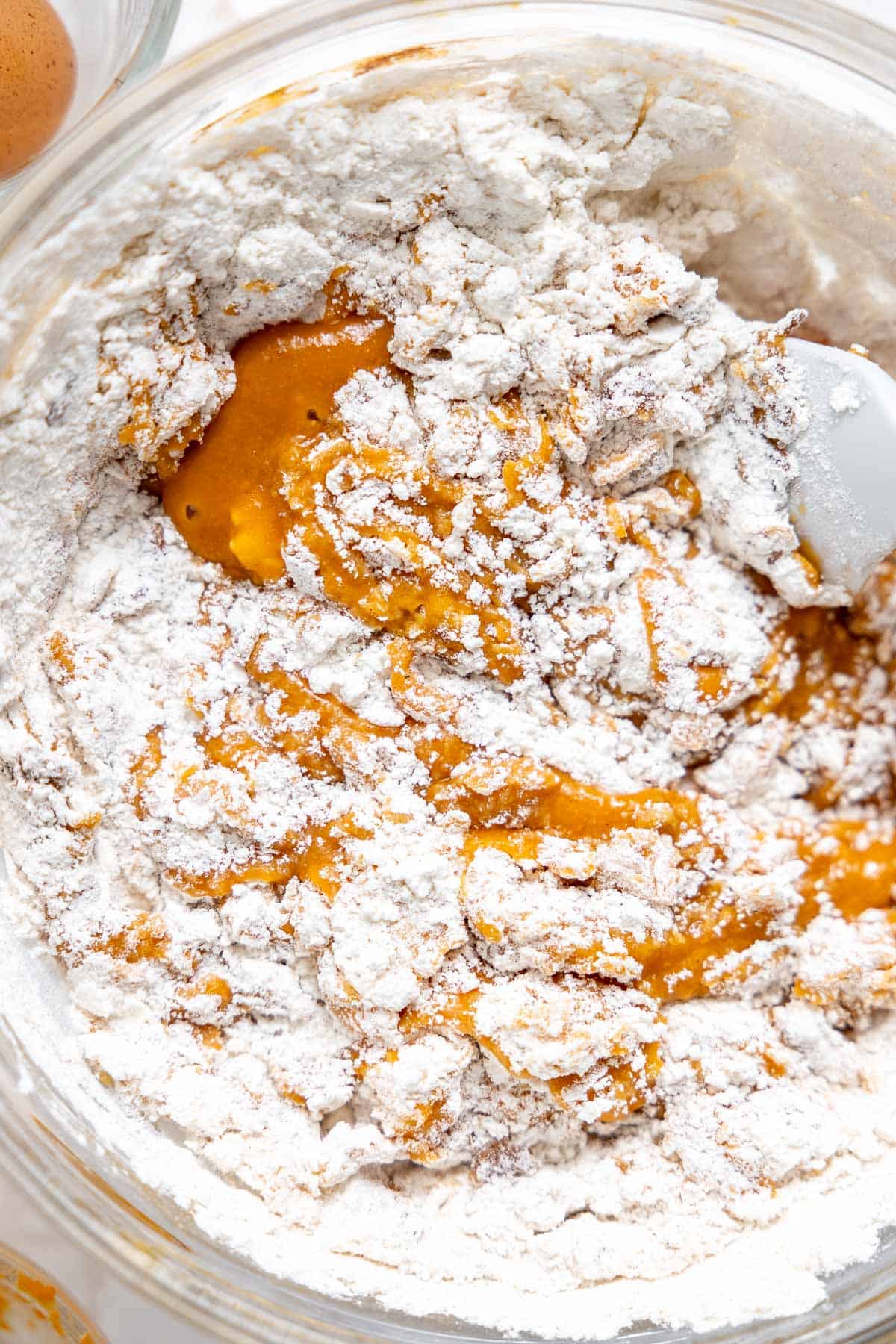 Mixing the dry ingredients into pumpkin muffin batter.