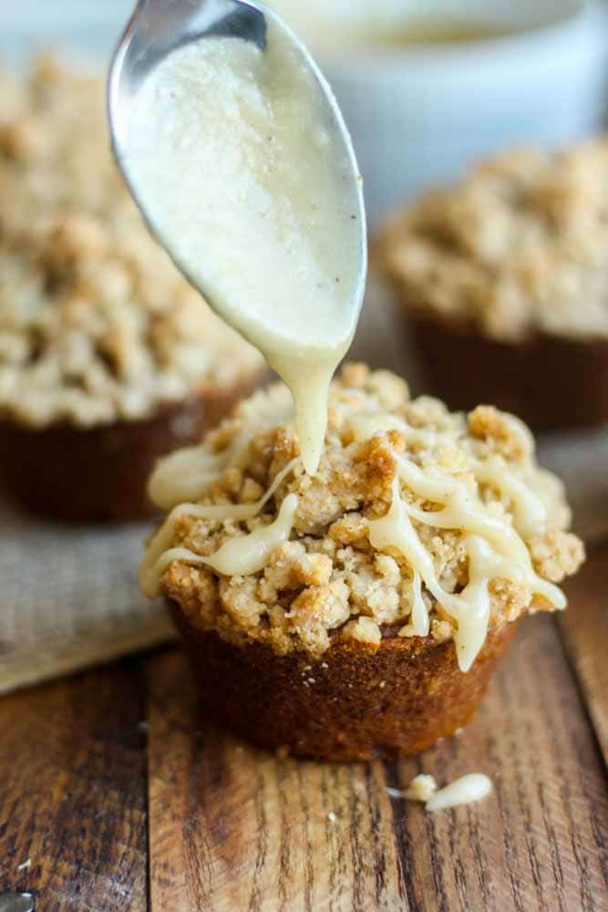 spoon drizzling icing onto pumpkin streusel muffins