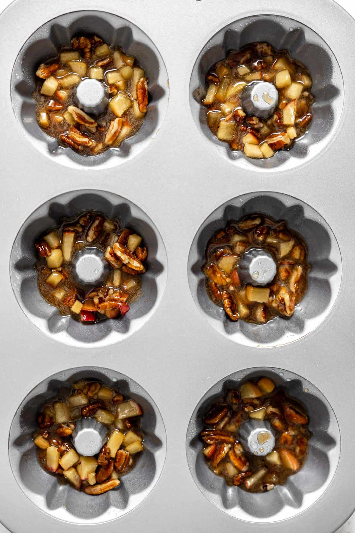 apple pecan topping separated into the bottom of mini bundt pans.