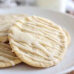 hand reaching for a soft maple sugar cookie resting on a white plate
