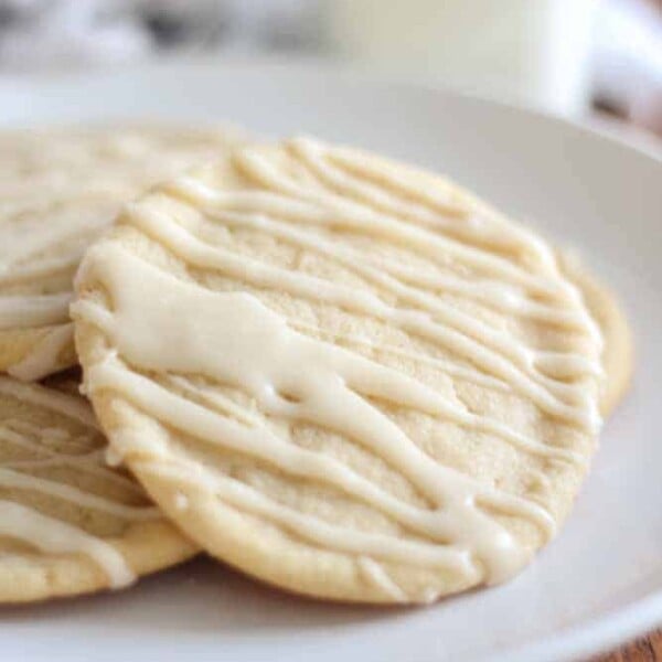 hand reaching for a soft maple sugar cookie resting on a white plate