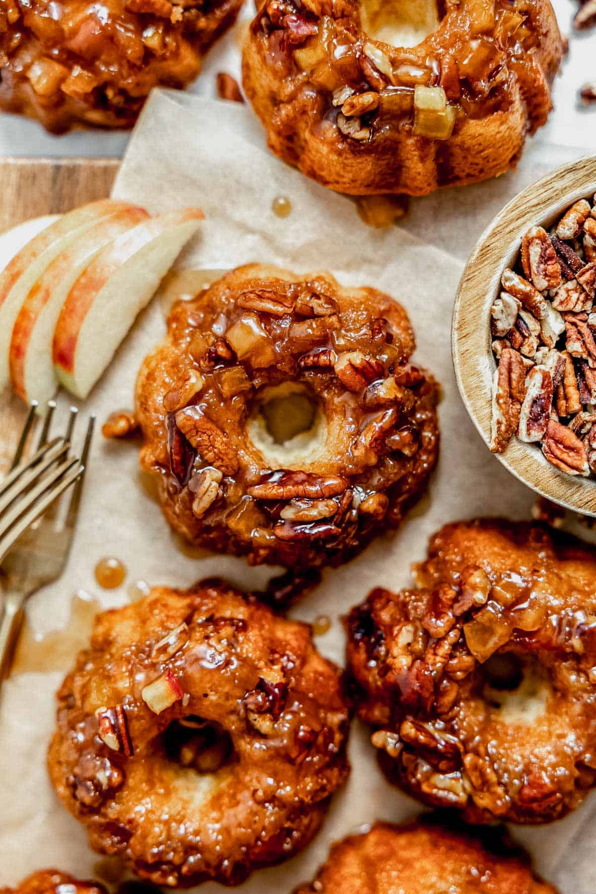 mini apple cakes topped with apples, pecans, and caramel on a serving tray.