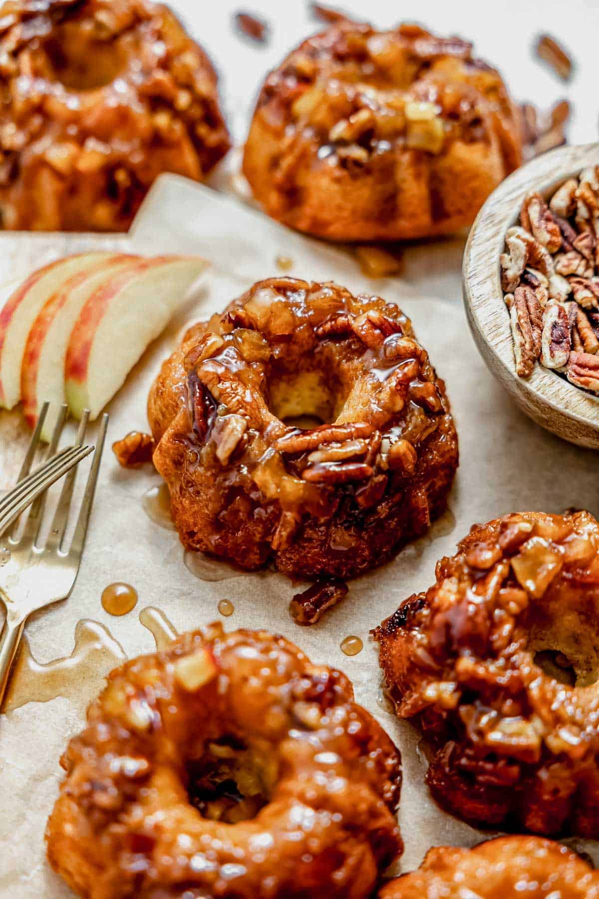 a batch of mini apple cakes on a cutting board with caramel apple topping.