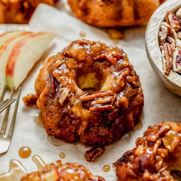 a mini apple cake with apple pecan caramel topping next to slices of apples.