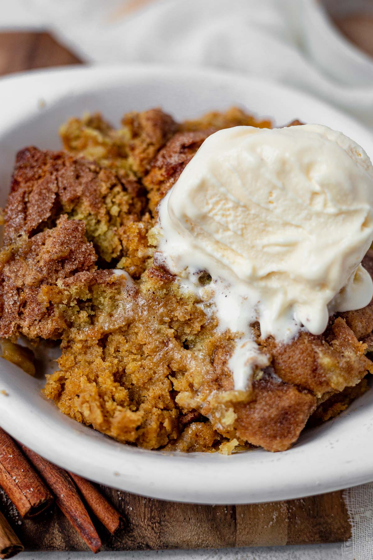 close up of the inside of pumpkin snickerdoodle cobbler with vanilla ice cream melting down the side