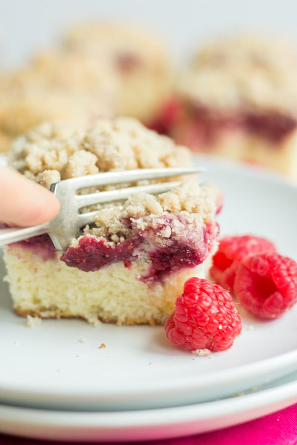 a fork digging into a piece of raspberry coffee cake 