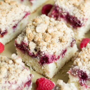 raspberry coffee cake cut into square and arranged evenly on a piece of brown parchment paper