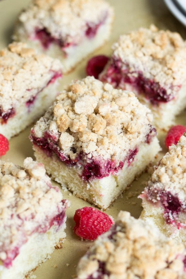 raspberry coffee cake cut into square and arranged evenly on a piece of brown parchment paper