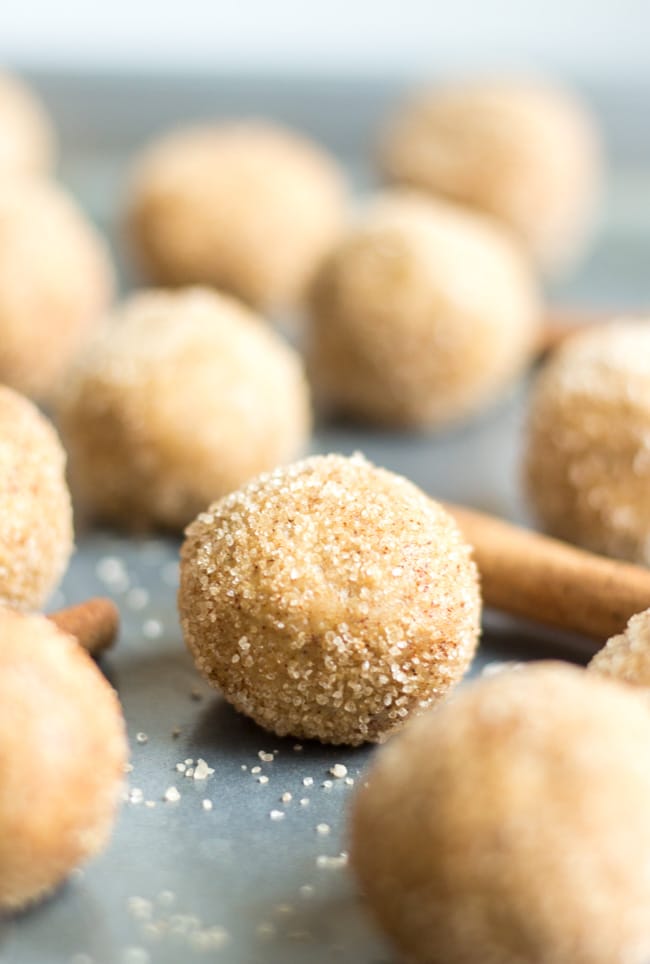 snickerdoodle energy balls on a sheet pan with cinnamon sicks