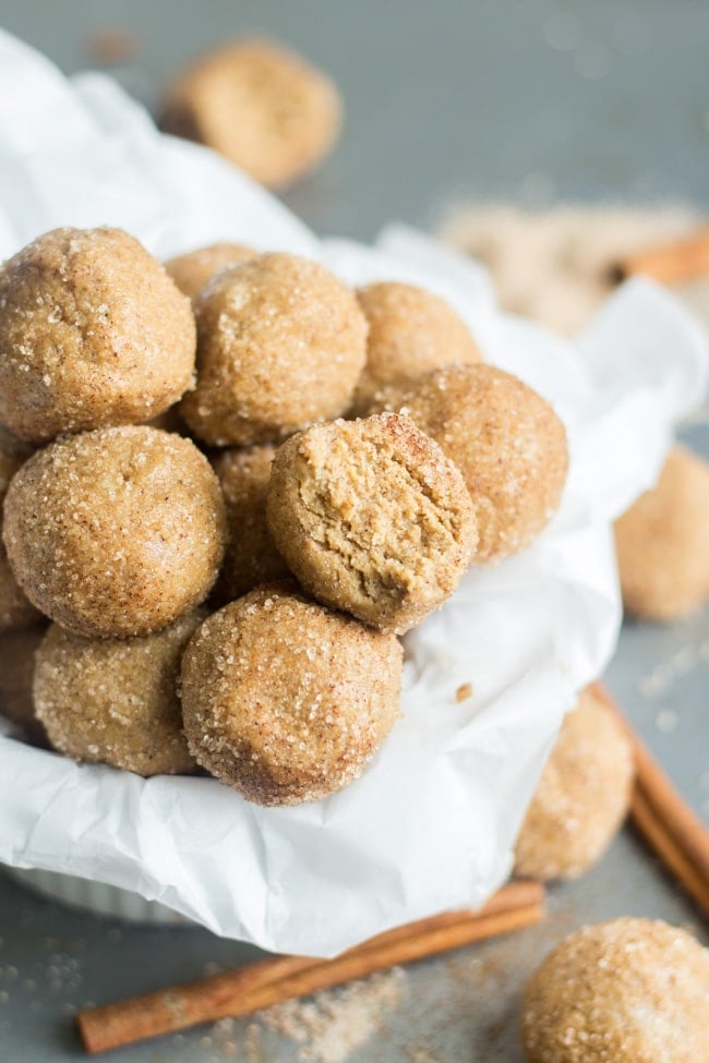 snickerdoodle protein balls on parchment paper with a bite taken out of one