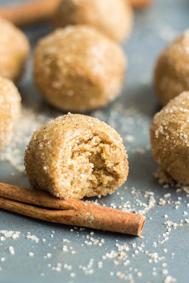 a bite taken out of a cinnamon sugar energy ball on a sheet pan