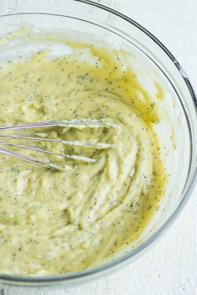 Healthier lemon poppy seed muffins batter in a glass bowl with a whisk in it