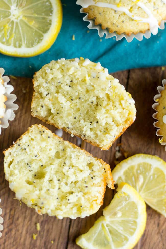 Healthier lemon poppy seed muffins cut in half with the inside of the halves facing upward on a counter top