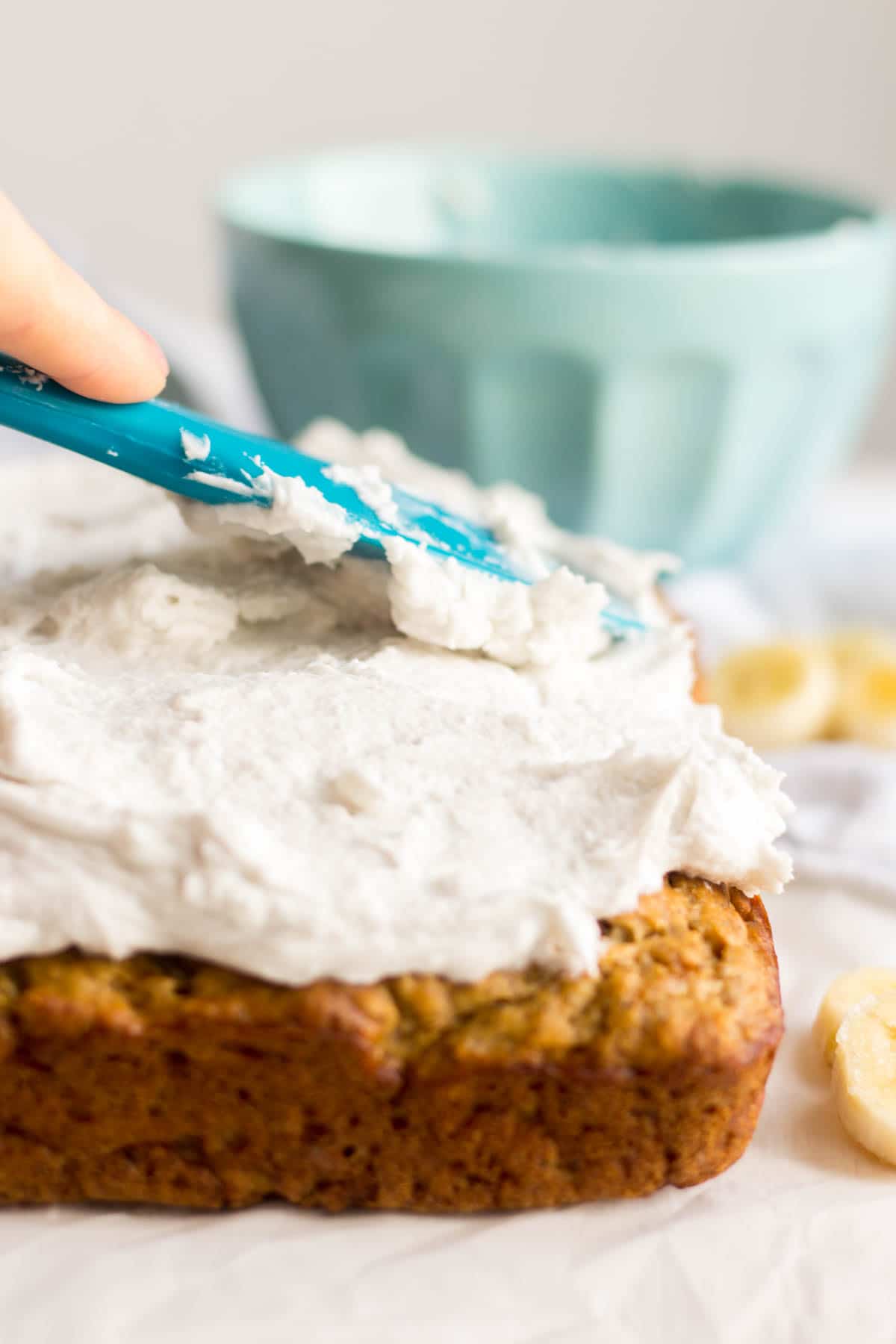 spreading dairy free whipped cream on top of healthy banana cake