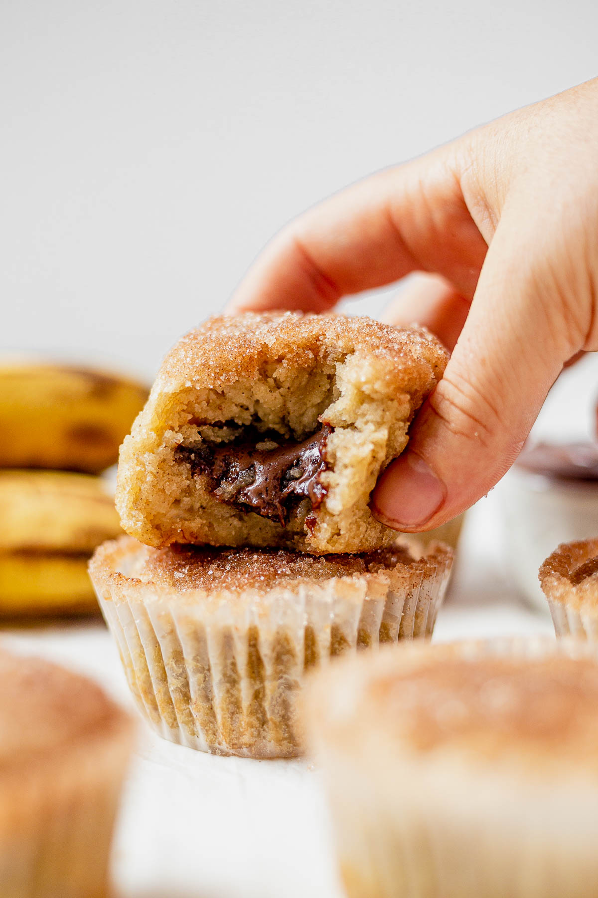 a hand picking up a nutella stuffed banana muffin up off a table