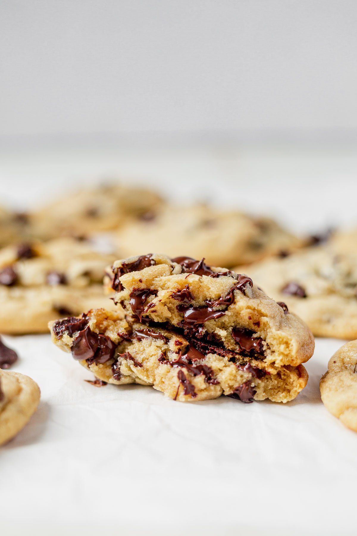 freshly baked chocolate chip cookie with pudding mix broken in half and sitting on parchment paper to show the gooey chocolate inside