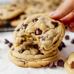 a gooey chocolate chip pudding cookie with a bite taken out sitting on top of another fresh baked cookie