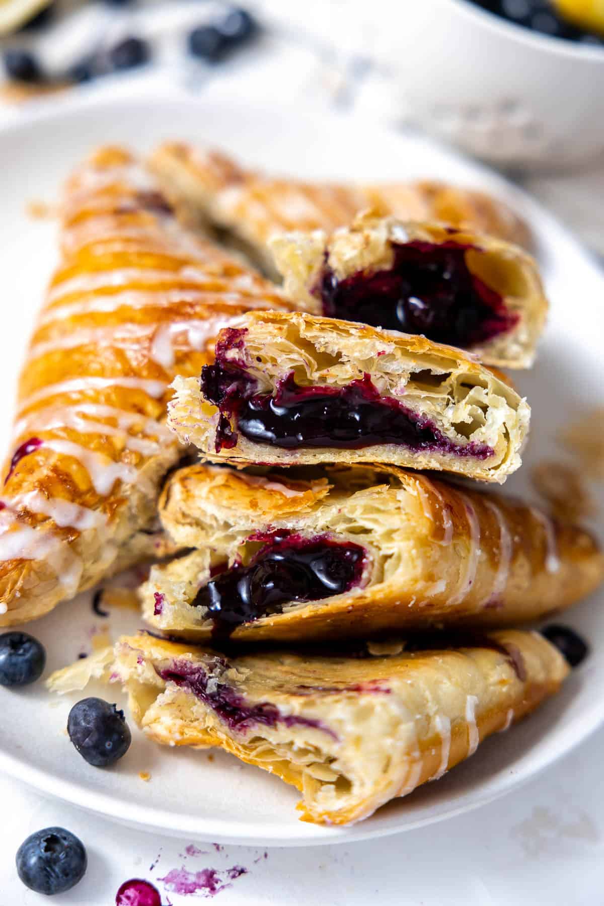 a plate of blueberry turnovers with one cut in half to see the blueberry filling.