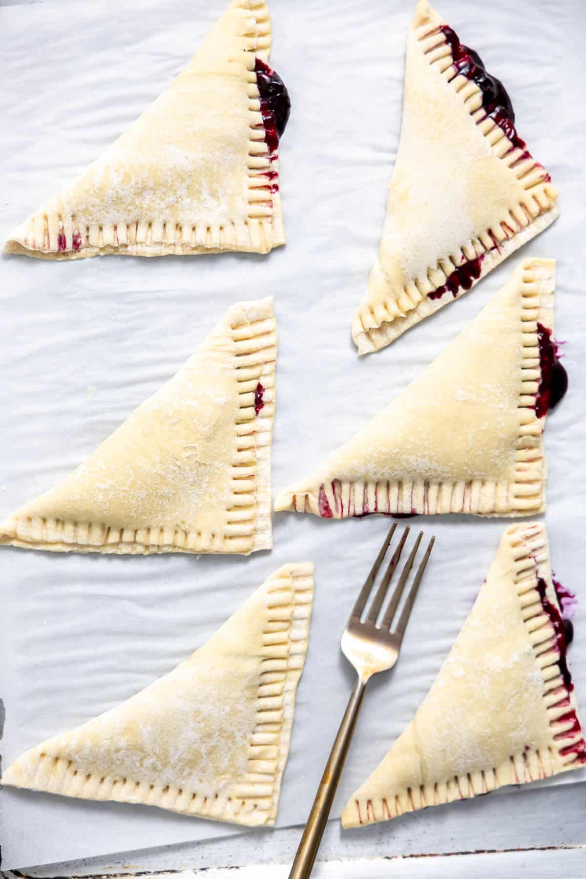 unbaked blueberry turnovers with the seams pressed from a fork.