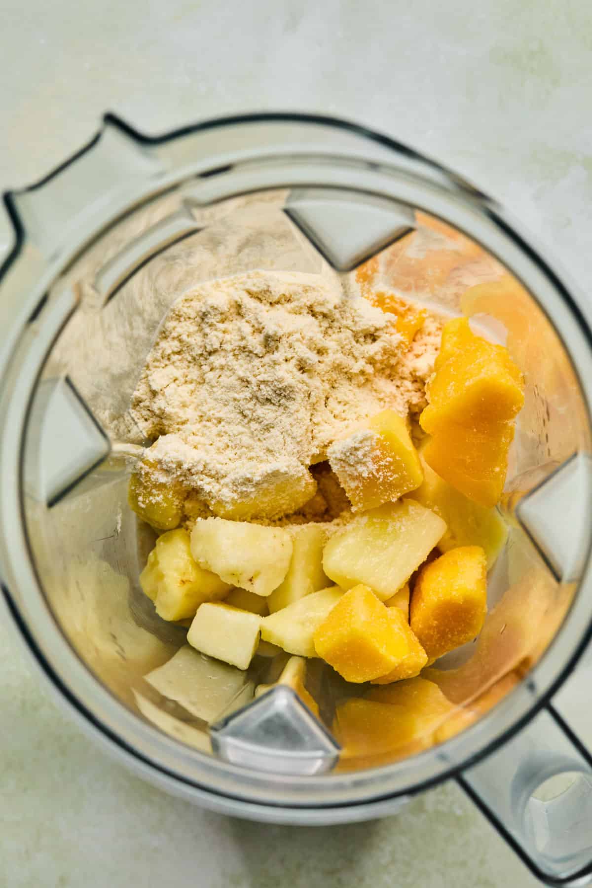 Vanilla protein powder and frozen fruit in a blender