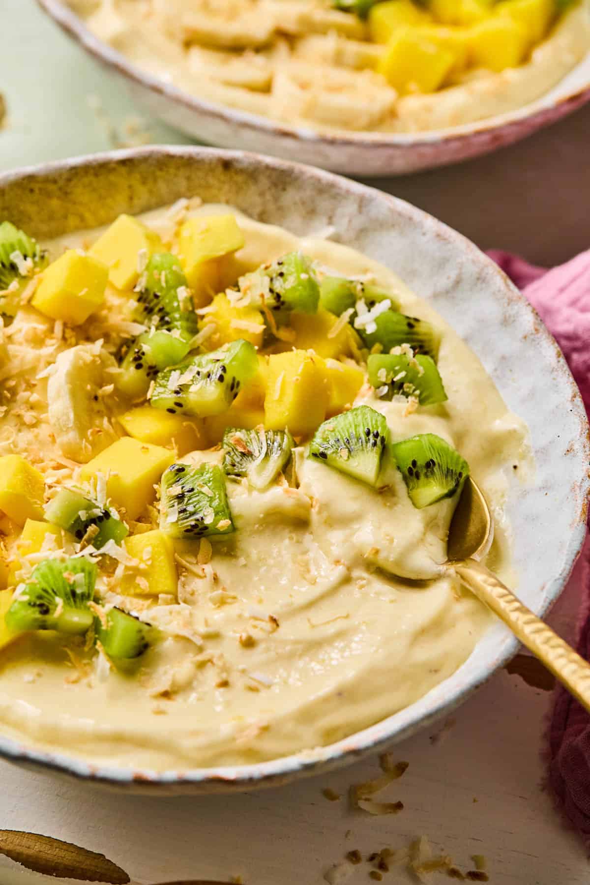 coconut smoothie bowl with all of the toppings and a spoon dipped into it