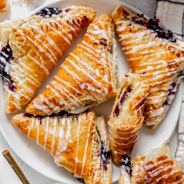 blueberry turnovers drizzled with glaze on a plate.