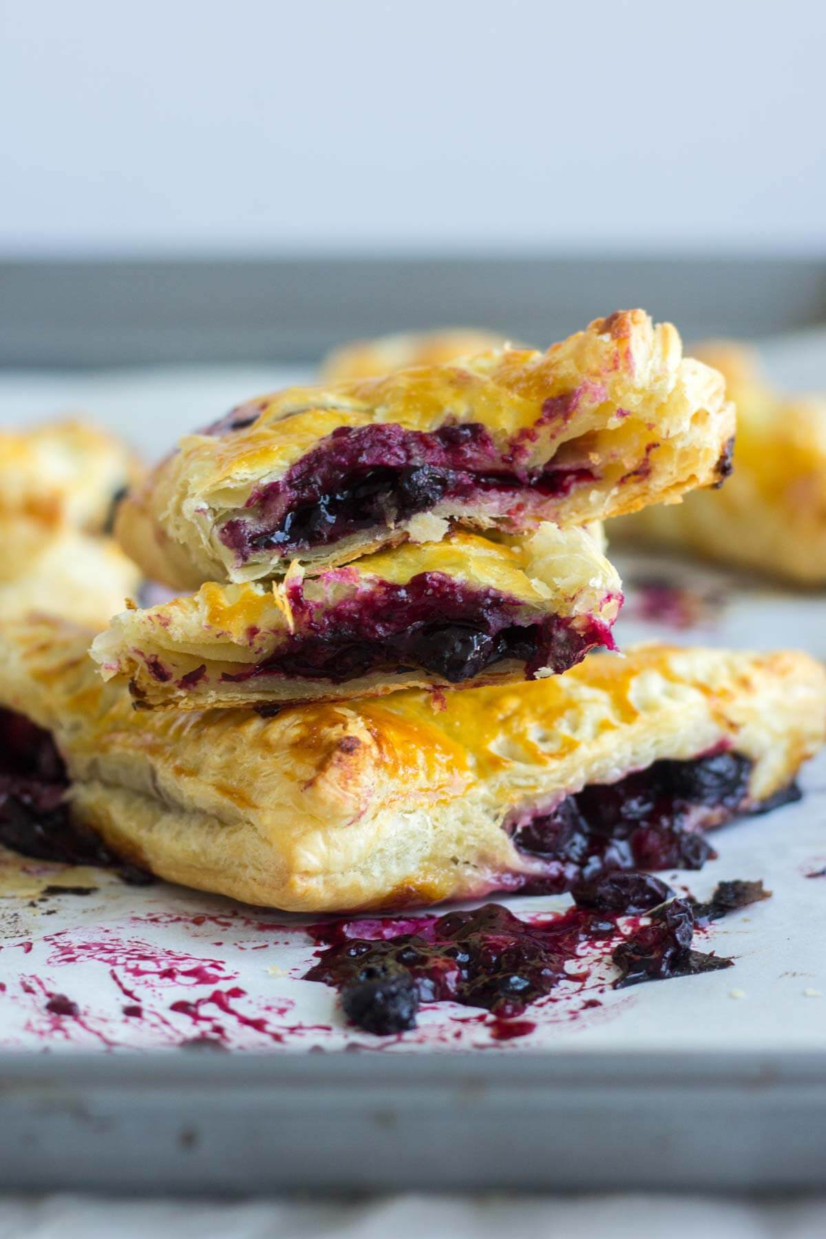 flaky lemon blueberry turnovers stacked on top of each other cut in half