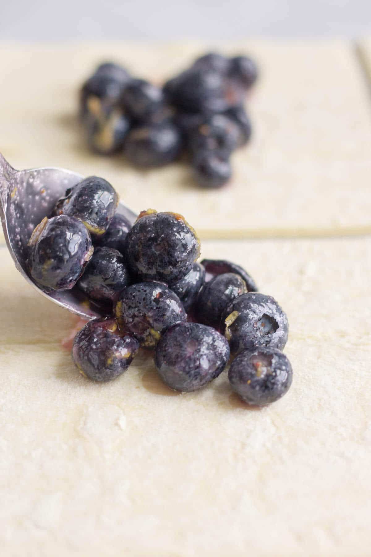 spoon filling puff pastry with blueberries and lemon