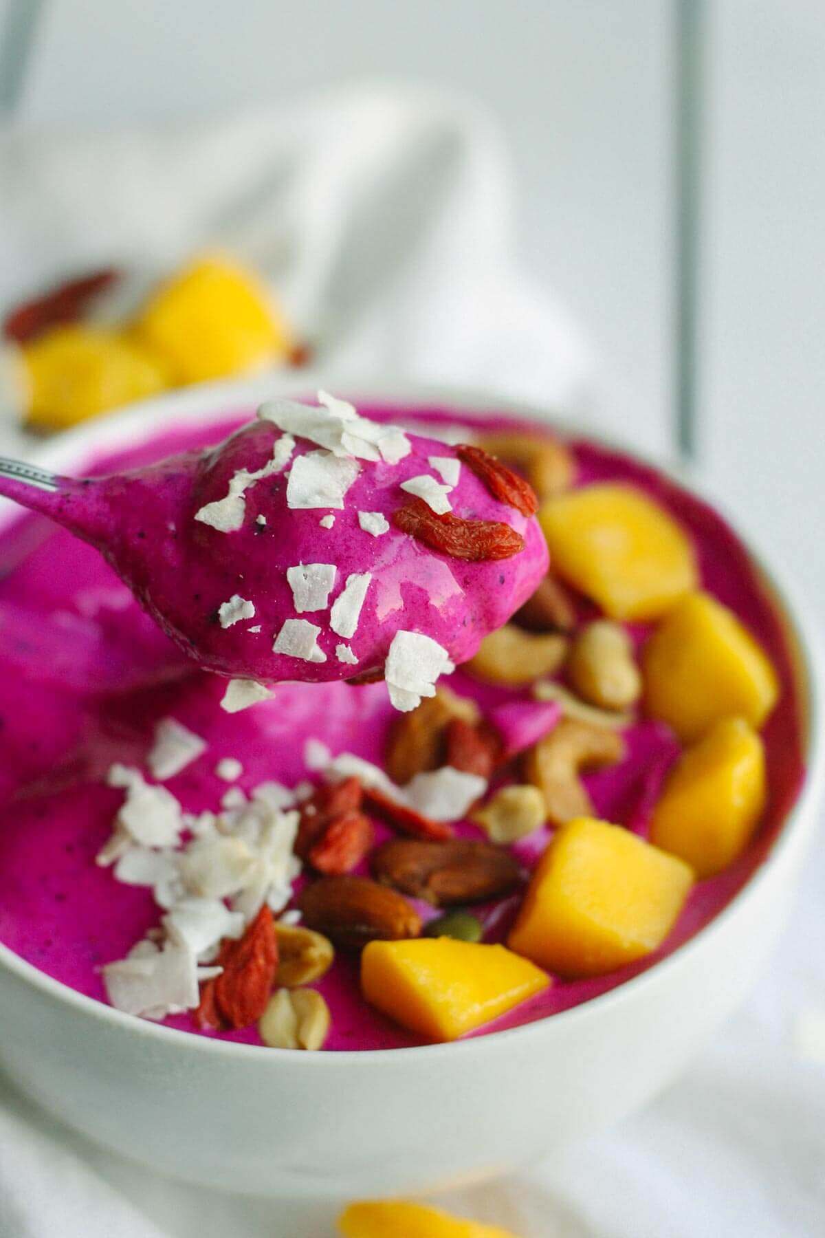 pitaya bowl recipe being scooped out with healthy toppings like goji berries