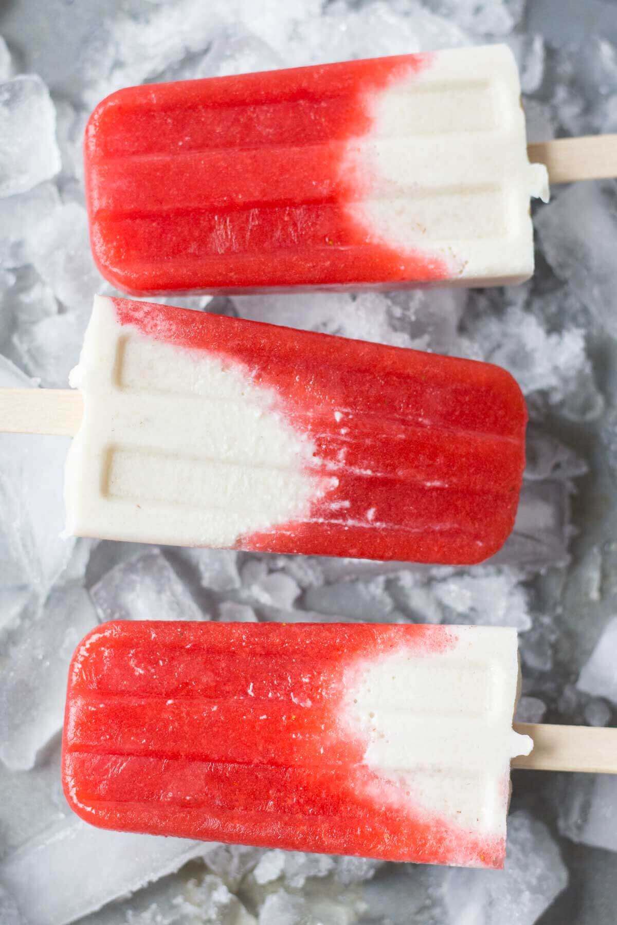 Strawberries and Cream Vegan Popsicles laying on ice