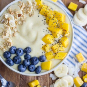 Tropical Coconut Smoothie Bowl on a table with a white and blue striped napkin with banana slices