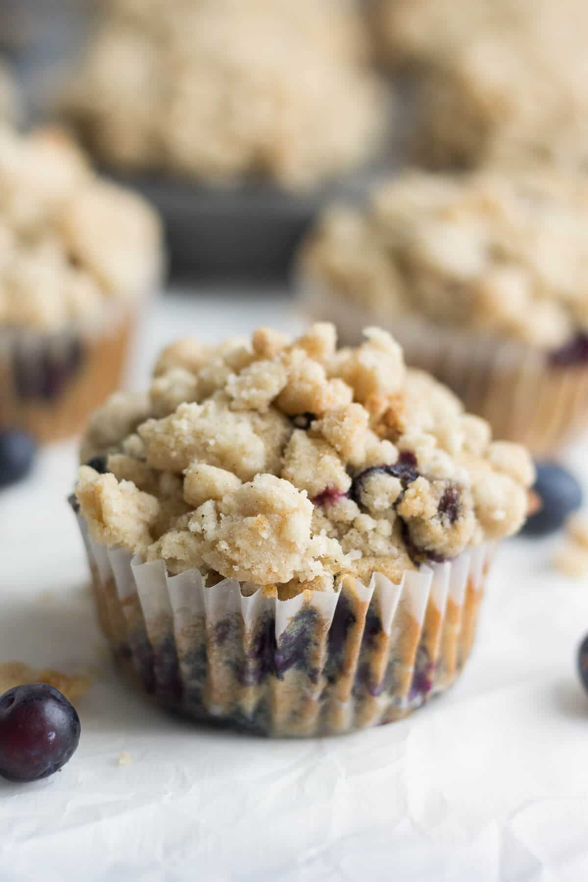blueberry muffin with crumb topping on a piece of parchment paper