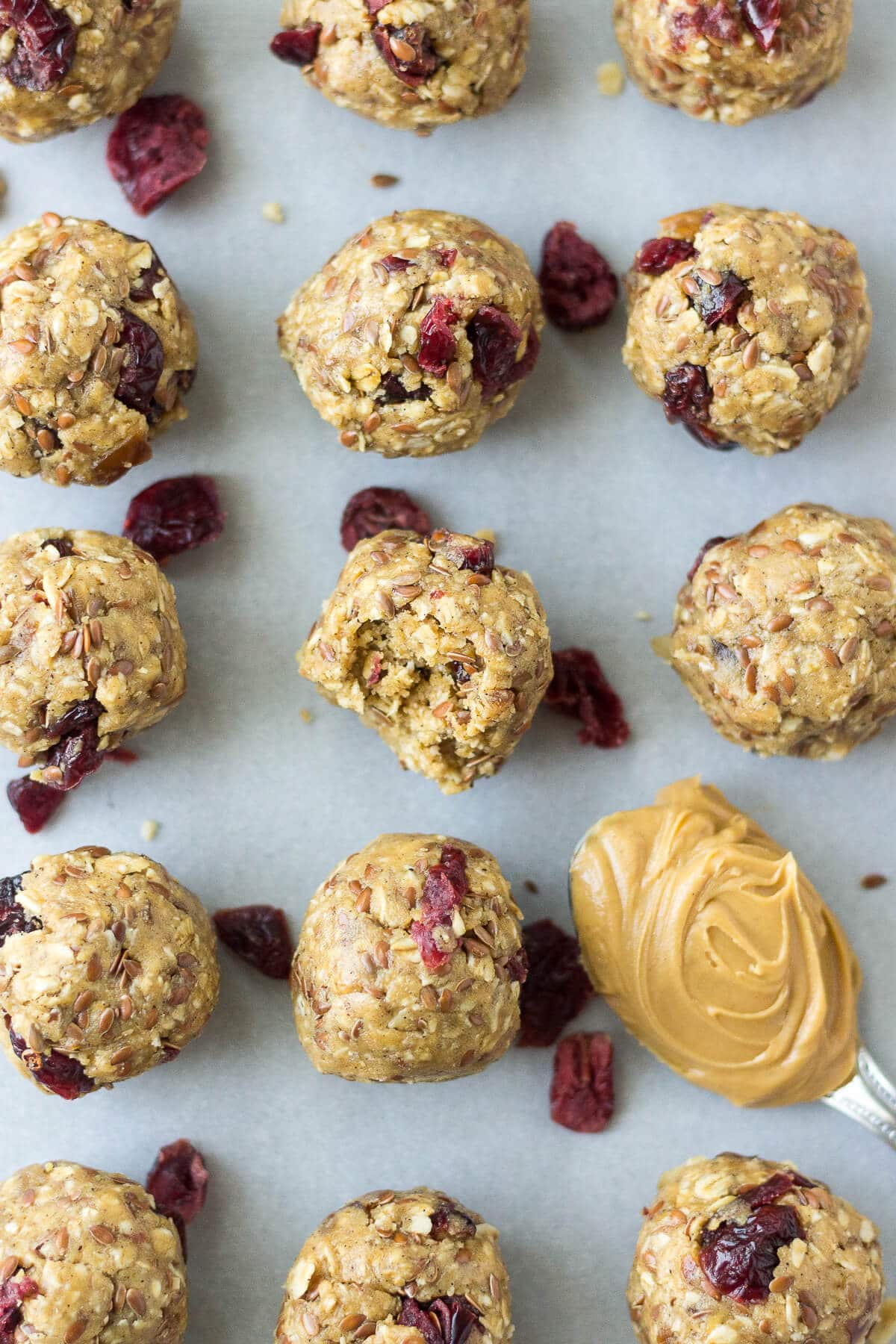 PB & J Protein Balls with a bite taken out of one and a spoonful of creamy peanut butter