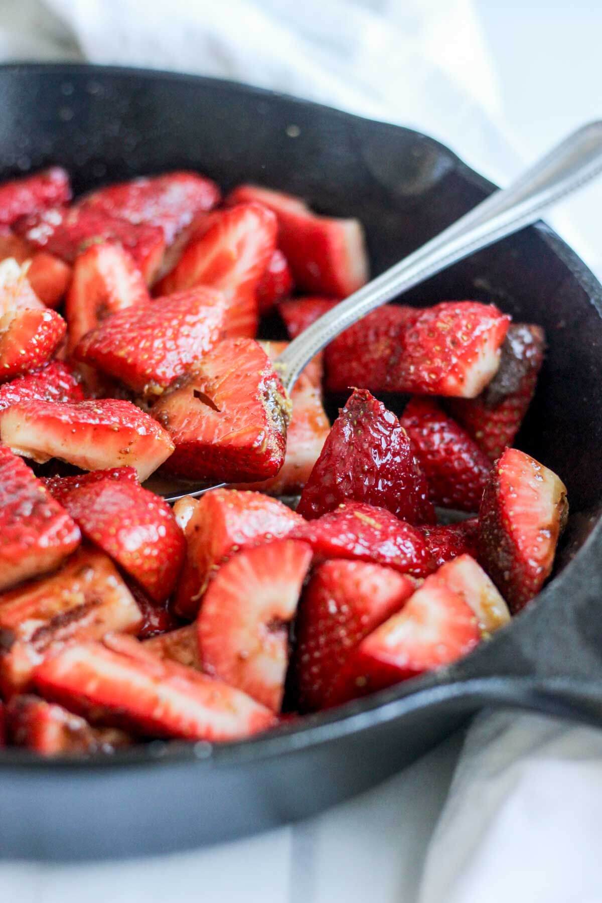 spoon dipping into roasted strawberry cobbler