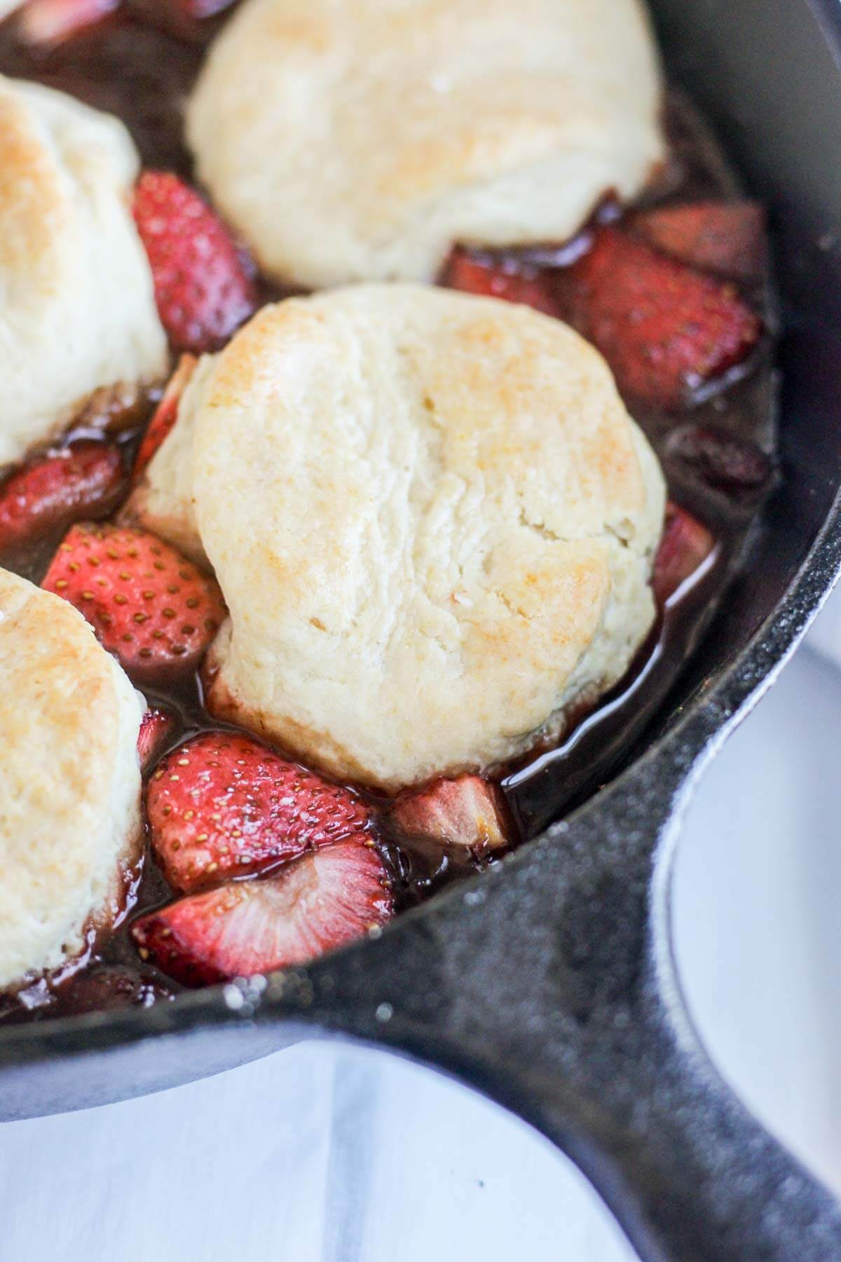 up close view of roasted strawberry cobbler in a cast iron skillet