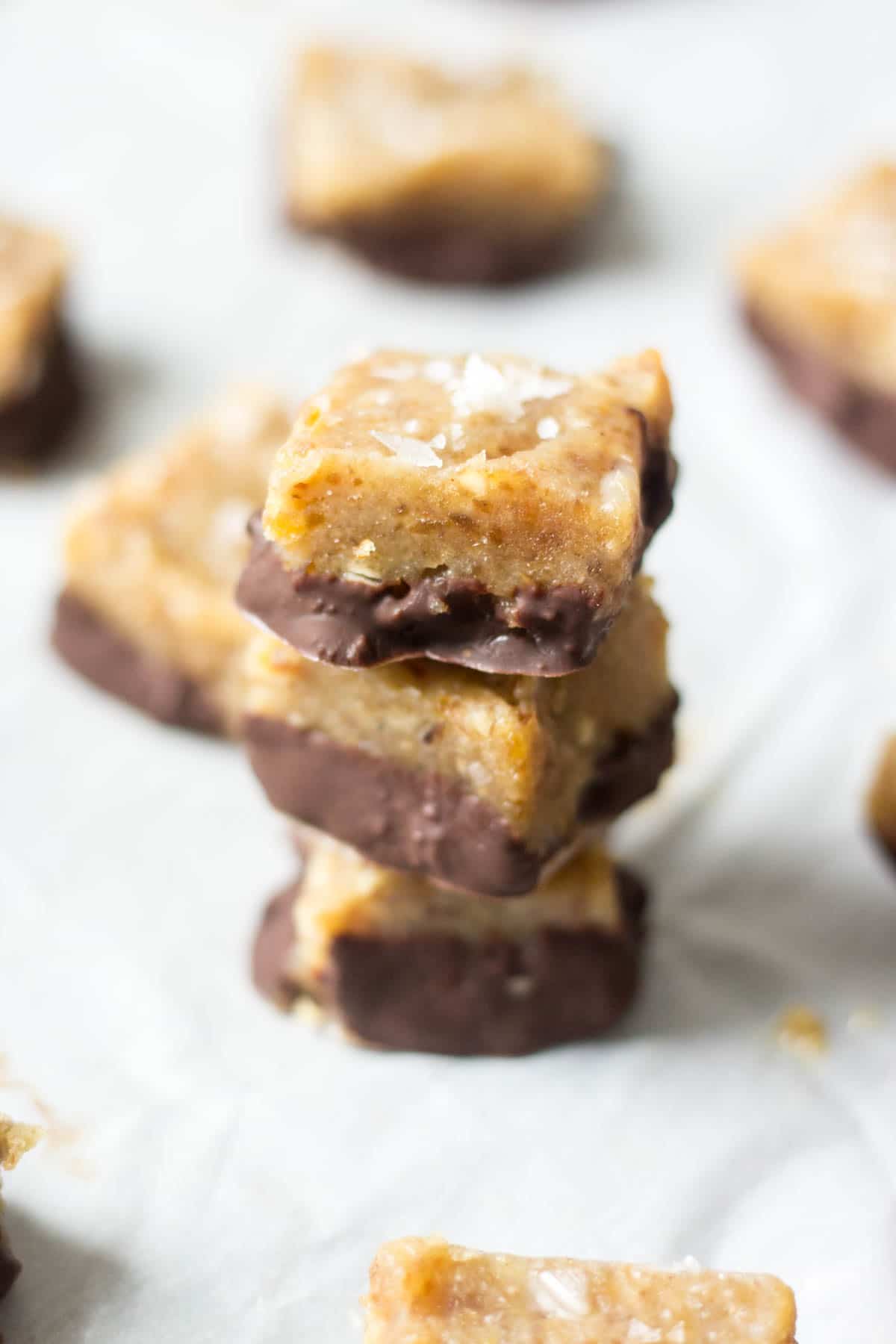 Three healthy salted caramels dunked in chocolate stacked on top of each other on a piece of parchment paper