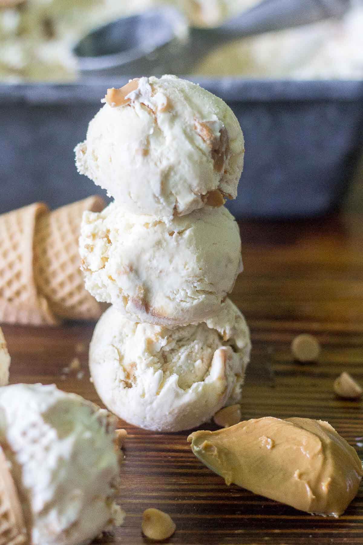 three scoops of no churn peanut butter ice cream stacked on top of each other on a counter